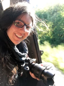 Fotografin Jennifer Scales sitzt lächelnd an der offenen Tür eines fahrenden Zuges